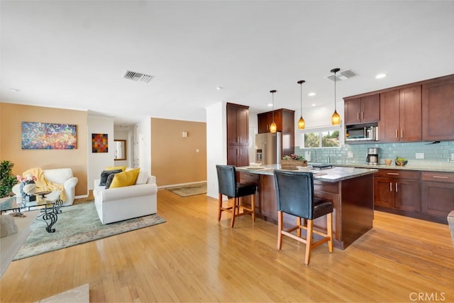 kitchen featuring a center island, visible vents, appliances with stainless steel finishes, and a breakfast bar area