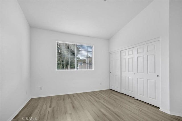 unfurnished bedroom with baseboards, lofted ceiling, and wood finished floors