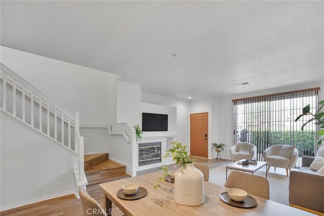 living room with visible vents, baseboards, stairway, a tile fireplace, and wood finished floors