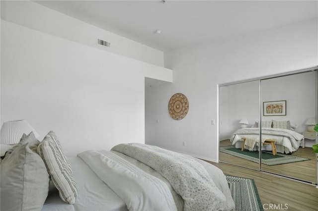 bedroom featuring a closet, visible vents, and wood finished floors