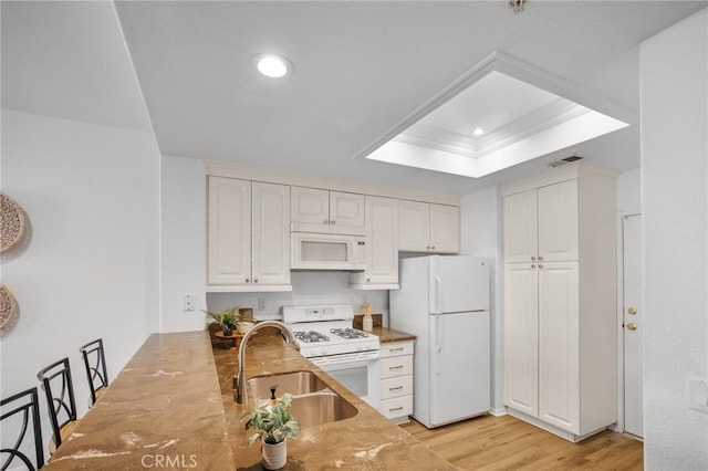 kitchen with light wood-style flooring, a sink, white cabinetry, white appliances, and a raised ceiling