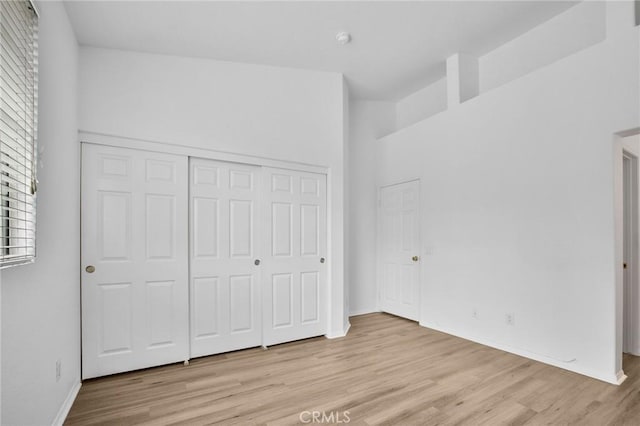 unfurnished bedroom with light wood-style floors, a closet, and baseboards