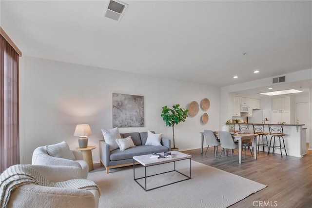 living area with light wood-style flooring, recessed lighting, visible vents, and baseboards