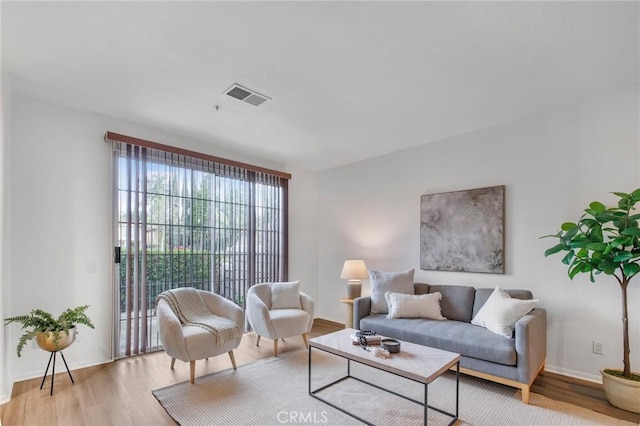 living room featuring wood finished floors, visible vents, and baseboards