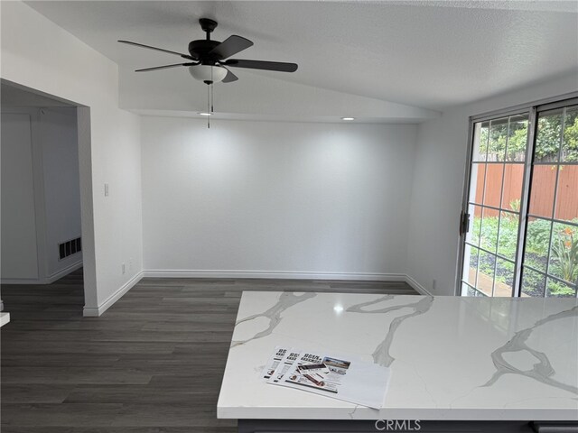 spare room featuring visible vents, baseboards, vaulted ceiling, a textured ceiling, and dark wood-style flooring