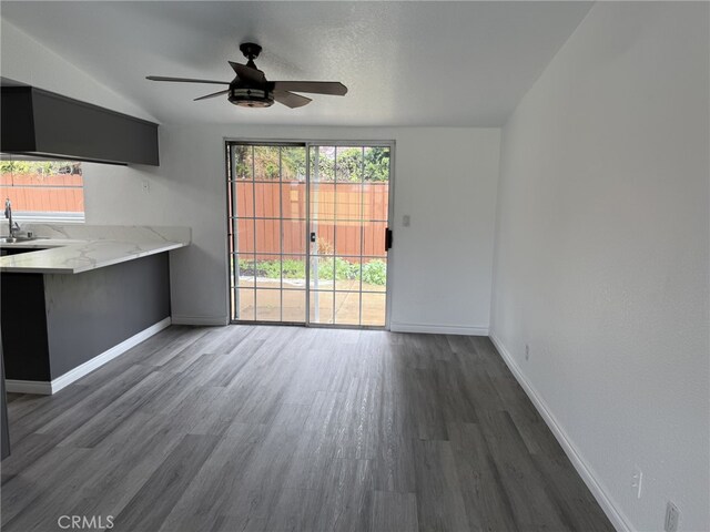 unfurnished living room with wood finished floors, baseboards, and ceiling fan