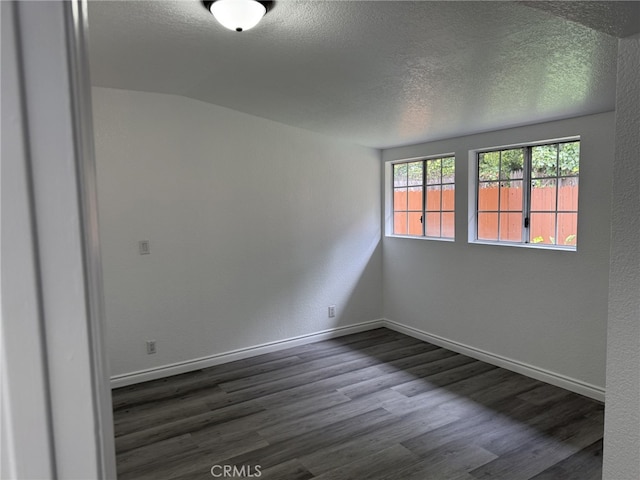 empty room with baseboards, a textured ceiling, dark wood-style floors, and a textured wall