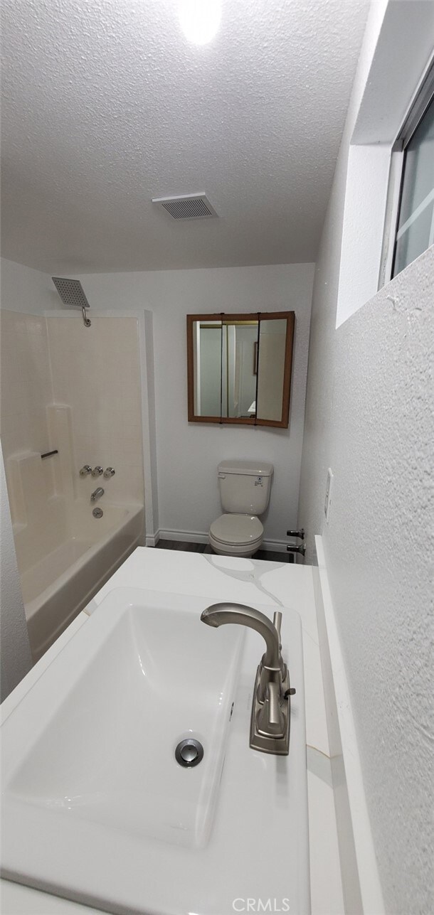 bathroom with visible vents, a textured ceiling, shower / tub combination, and a sink