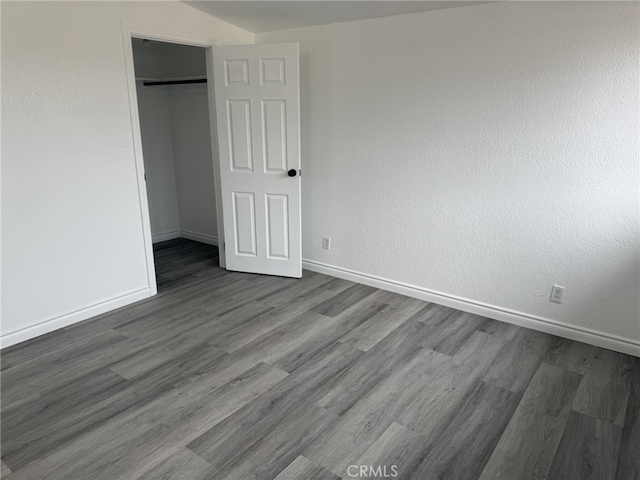 unfurnished bedroom featuring a closet, baseboards, and dark wood-style flooring