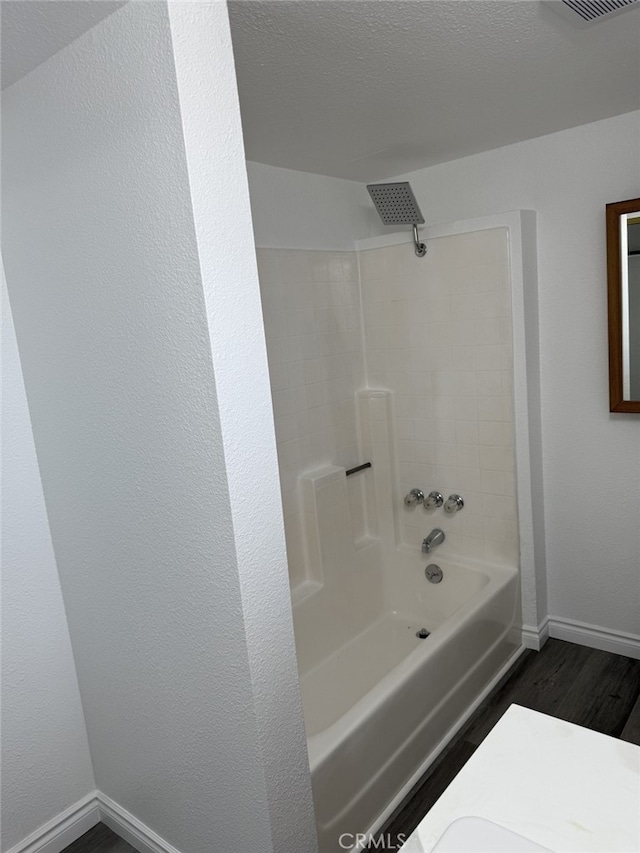 full bathroom featuring visible vents, baseboards, bathing tub / shower combination, wood finished floors, and a textured ceiling