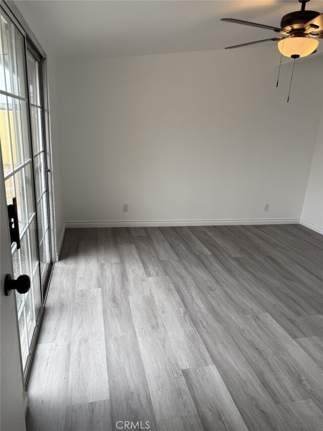 empty room with ceiling fan, baseboards, and wood finished floors