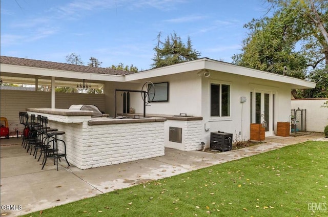 rear view of property featuring outdoor wet bar, exterior kitchen, french doors, and a patio