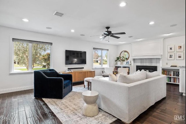 living room featuring recessed lighting, dark wood-type flooring, and a fireplace