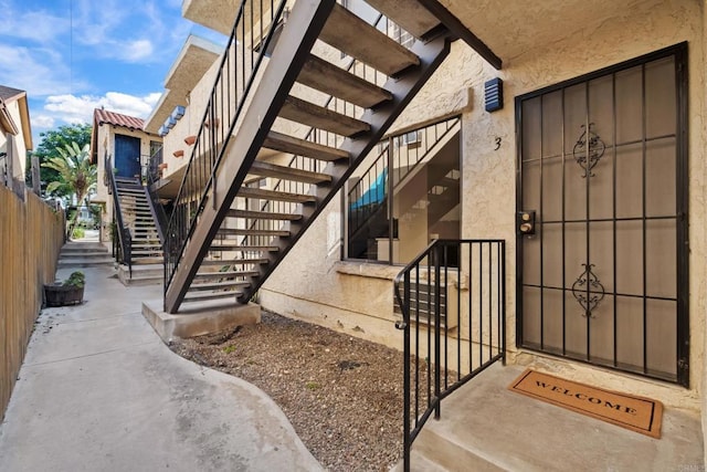 property entrance featuring fence and stucco siding