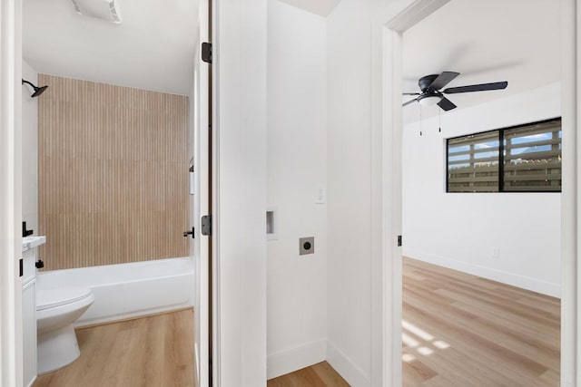 bathroom featuring toilet, shower / tub combination, wood finished floors, baseboards, and ceiling fan