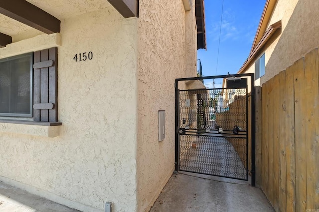 view of side of property with stucco siding and a gate