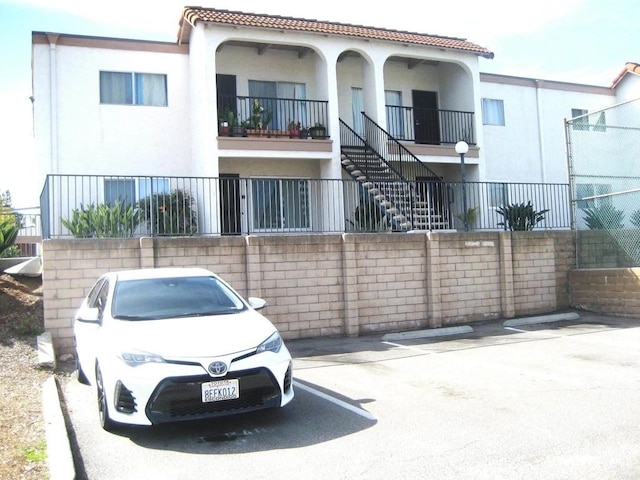 view of property featuring stairway and uncovered parking