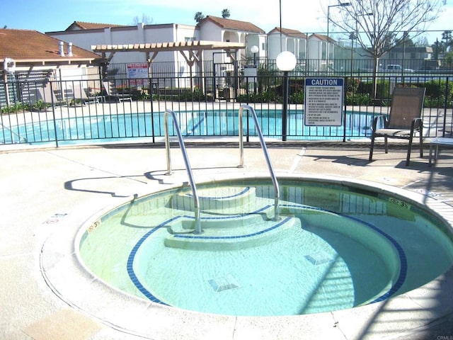 pool featuring a hot tub, a patio, and fence