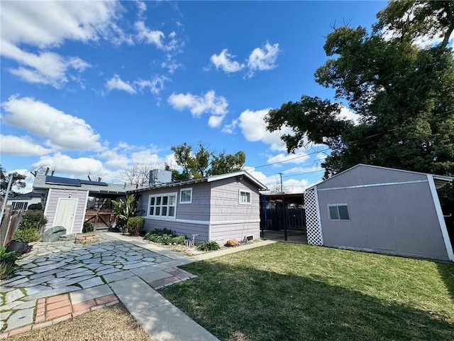 rear view of property featuring a yard, an outdoor structure, a shed, and fence