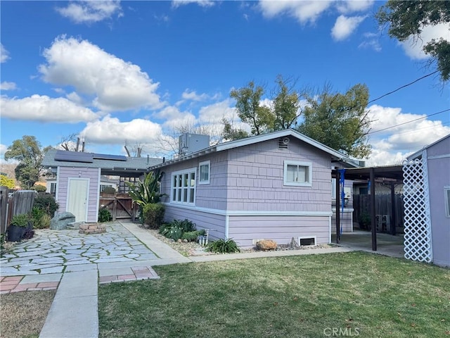 rear view of property featuring a yard, an outbuilding, a patio area, and fence