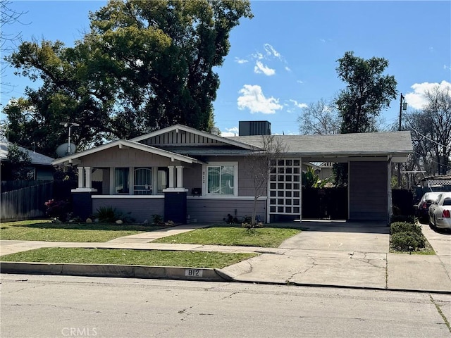 single story home with a carport, concrete driveway, a front lawn, and fence