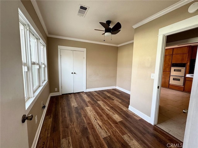 unfurnished bedroom featuring dark wood finished floors, crown molding, baseboards, and visible vents