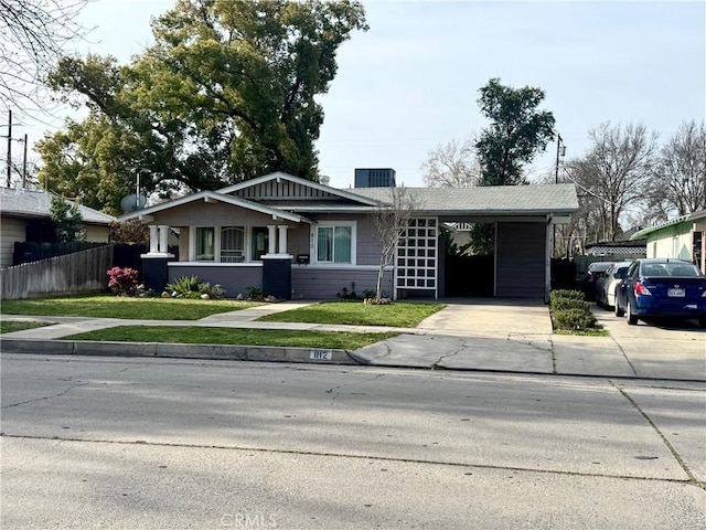 view of front of home with an attached carport, a front yard, driveway, and fence