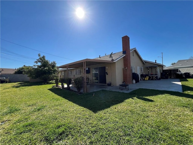 back of property featuring a yard, a patio, a chimney, and fence