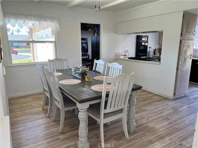 dining area with baseboards, beam ceiling, and light wood-style floors