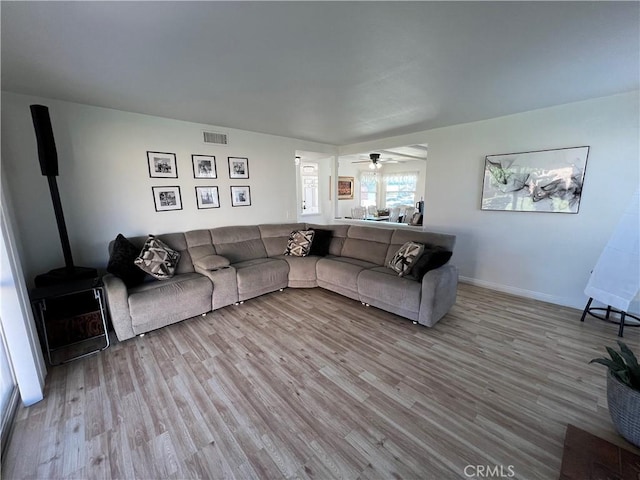 living area with visible vents, baseboards, wood finished floors, and a wood stove