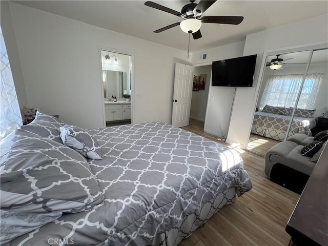 bedroom with visible vents, ceiling fan, wood finished floors, a closet, and ensuite bath