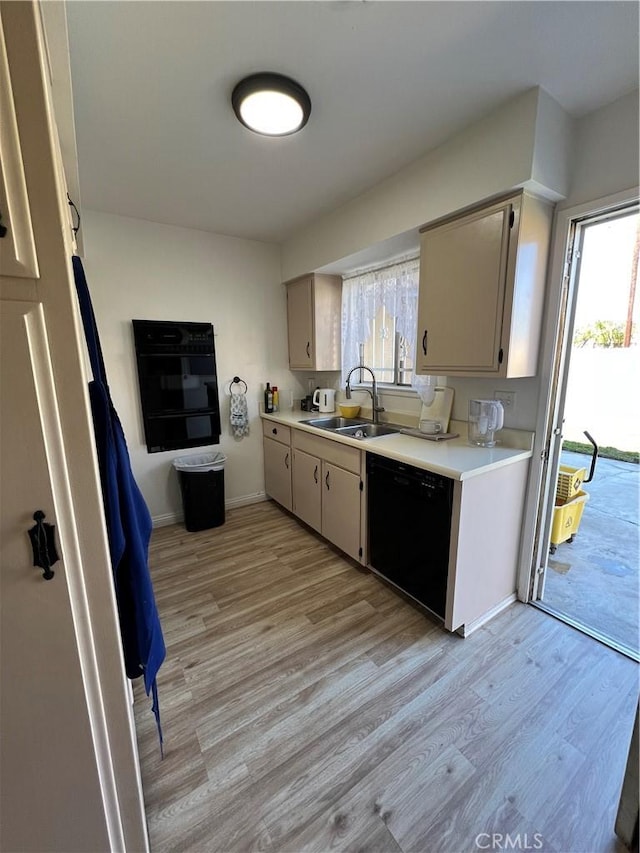 kitchen featuring dishwasher, light countertops, light wood-style floors, and a sink