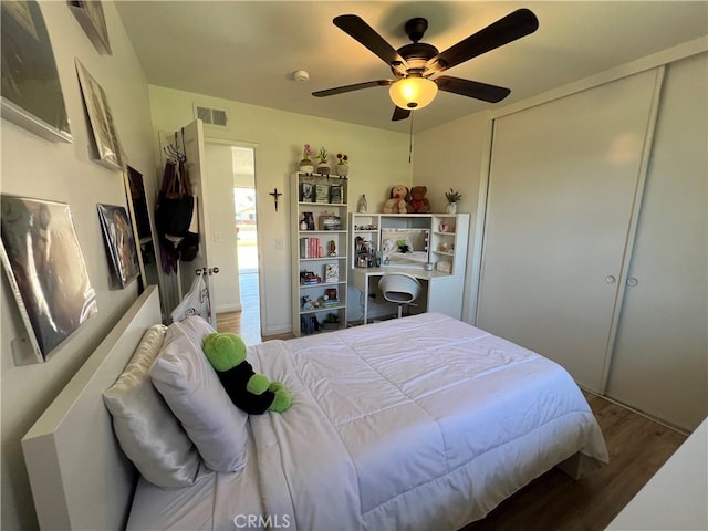 bedroom with a closet, visible vents, ceiling fan, and wood finished floors