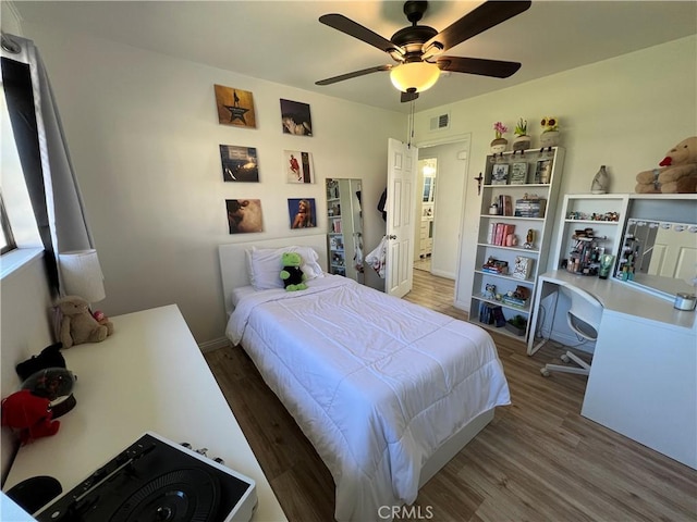 bedroom featuring a ceiling fan, wood finished floors, visible vents, and baseboards