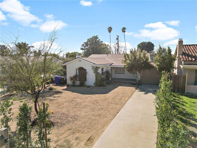 view of front of property featuring fence, driveway, and stucco siding