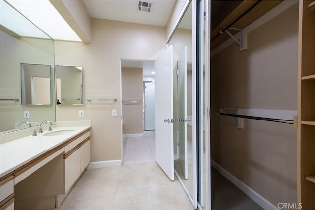 full bath with visible vents, vanity, tile patterned flooring, baseboards, and a spacious closet