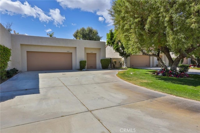 pueblo-style home with stucco siding, driveway, and an attached garage