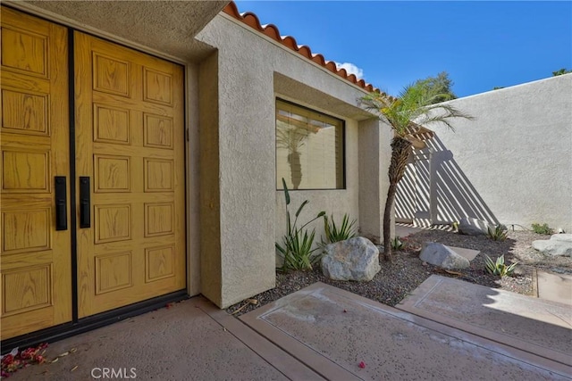 doorway to property with a tile roof and stucco siding