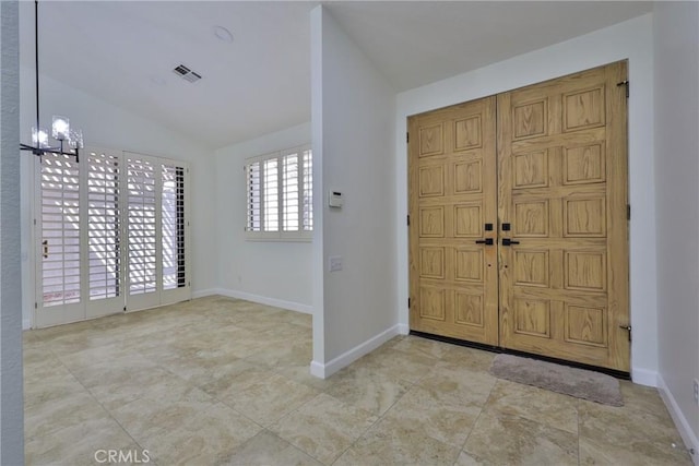 entrance foyer with baseboards, lofted ceiling, visible vents, and an inviting chandelier