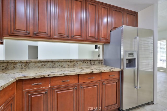kitchen featuring light tile patterned flooring, stainless steel fridge with ice dispenser, light stone countertops, and dark brown cabinets