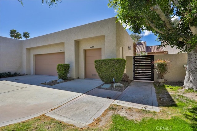 pueblo-style home featuring stucco siding, concrete driveway, and an attached garage