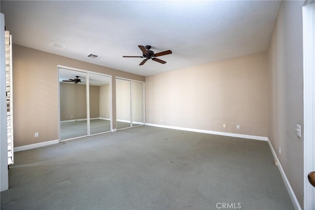 unfurnished bedroom featuring visible vents, ceiling fan, baseboards, and multiple closets