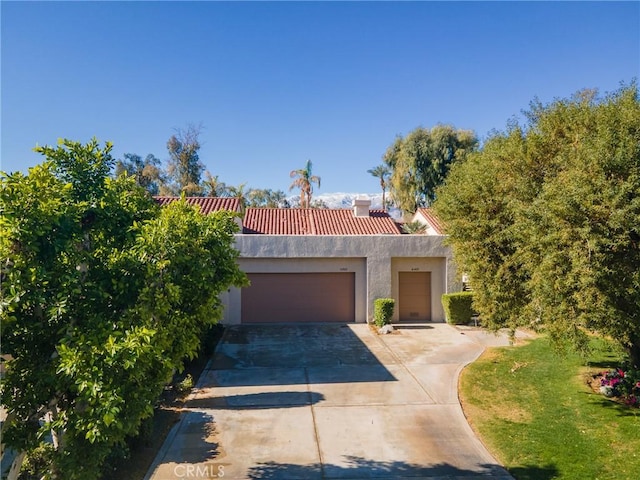 view of front of home with a tiled roof, driveway, stucco siding, and an attached garage