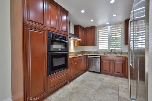 kitchen with light stone countertops, recessed lighting, stainless steel appliances, wall chimney exhaust hood, and a sink