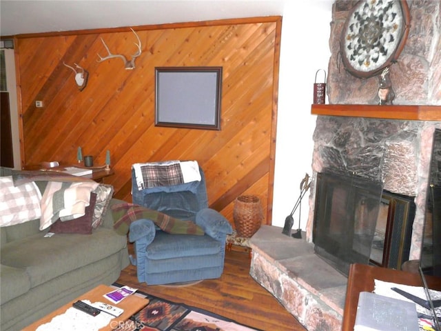 living room with wood finished floors, a fireplace, and wood walls