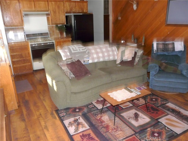 living area with dark wood-style floors and wood walls