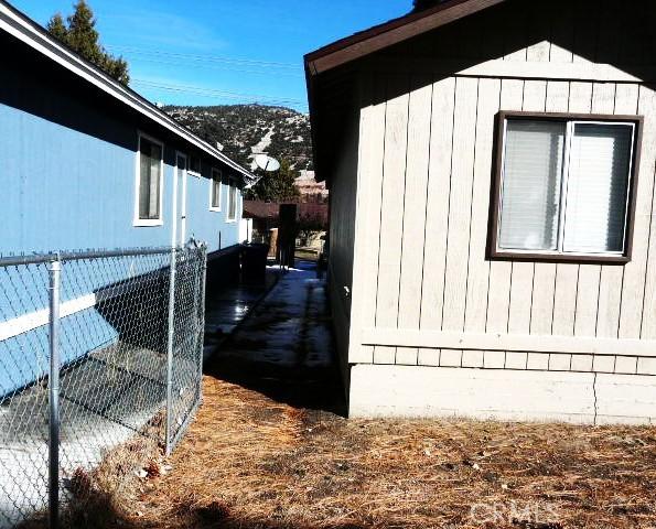 view of side of home with a mountain view and fence