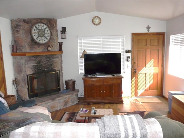 living room with lofted ceiling and a stone fireplace