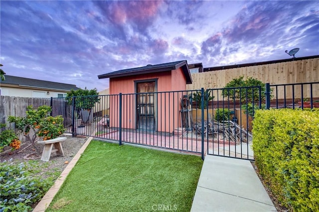 back of property at dusk with a yard, a patio, an outbuilding, and a fenced backyard