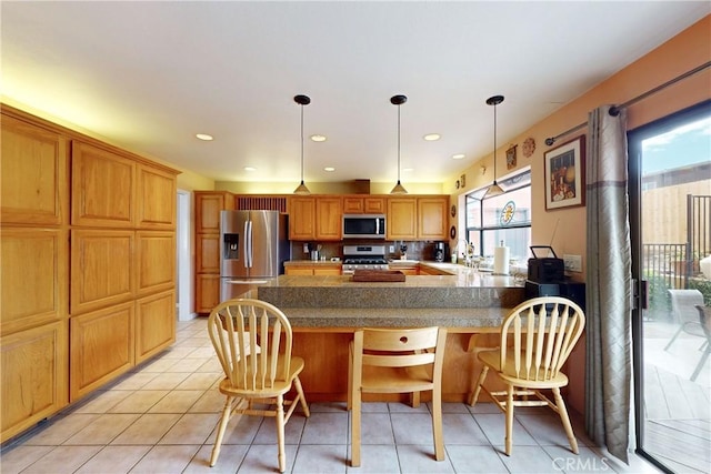 kitchen with light tile patterned floors, a peninsula, appliances with stainless steel finishes, and a breakfast bar area